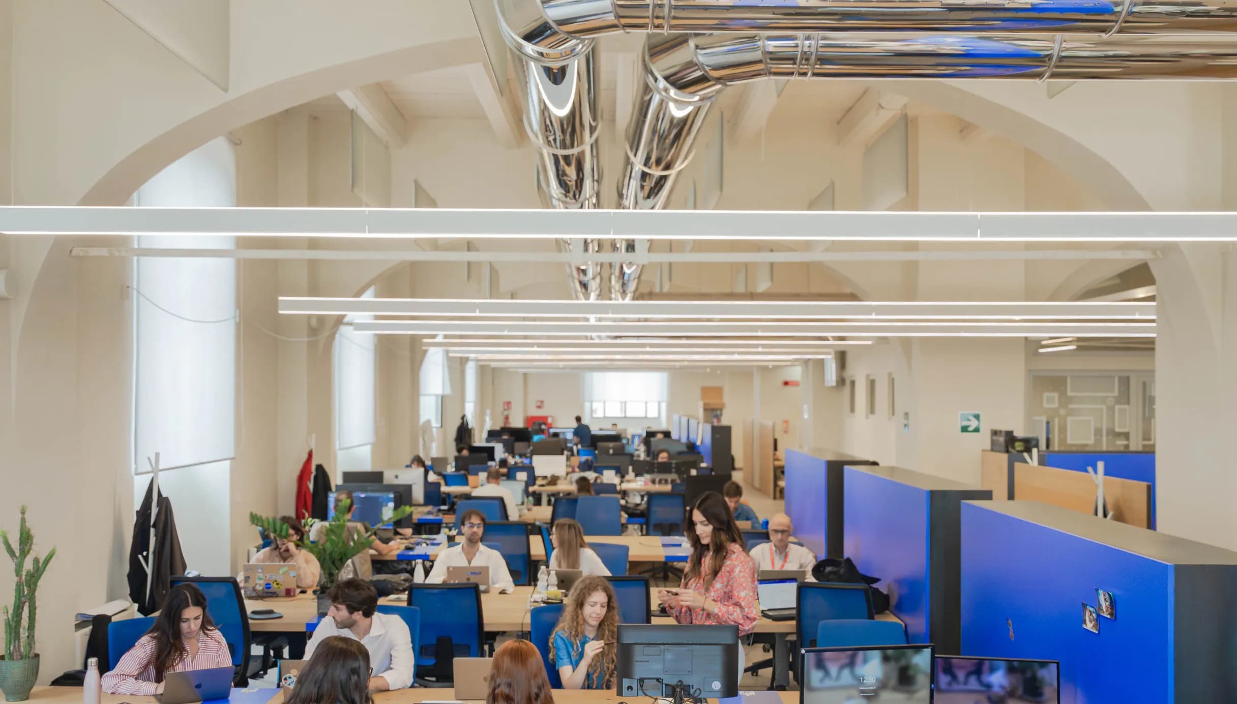 Ampio open space del coworking di Nana Bianca a Firenze, con scrivanie condivise, sedute ergonomiche e un ambiente luminoso ideale per il lavoro in team e la produttività.